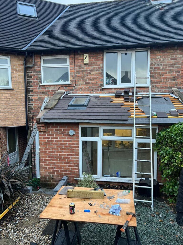 This is a photo of a roof extension that is having new roof tiles installed. This is a photo taken from the roof ridge looking down a tiled pitched roof on to a flat roof. Works carried out by Isleham Roofing Repairs