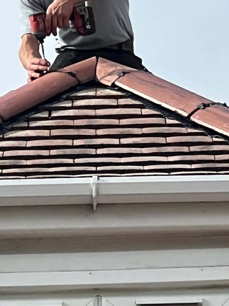 This is a photo of one of the operatives of Isleham Roofing Repairs installing new ridge tiles